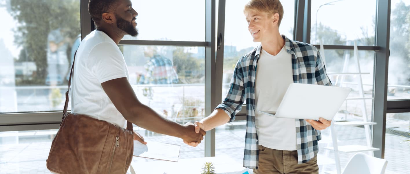 two young men smiling and shaking hands