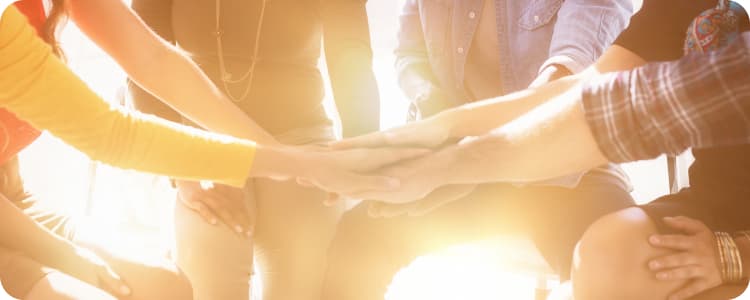 a group of employees putting their hands together in a huddle