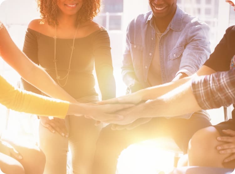 a group of employees putting their hands together in a huddle