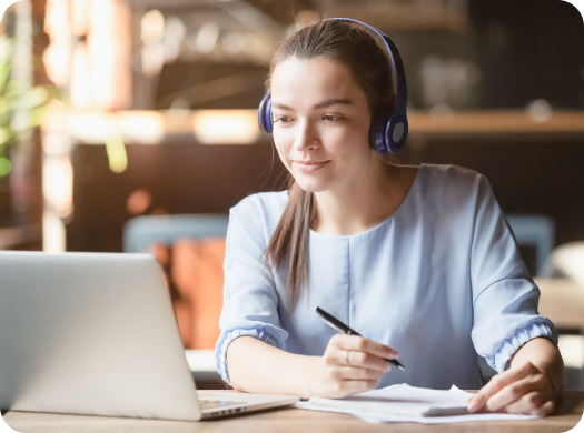 Young woman wearing headphones works on a laptop independently